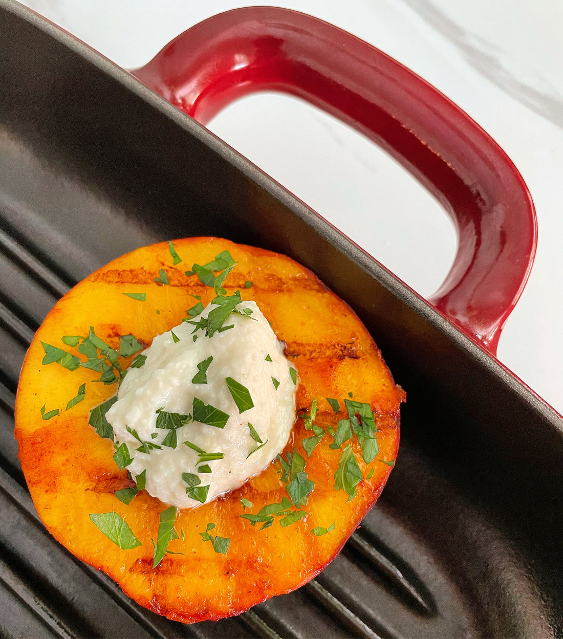 Grilled peach filled with ricotta peach topped with pistachios and mint