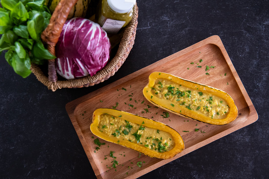 picture of red lentil oup inside of a delicata squash split in half with herbs and a wooden spoon