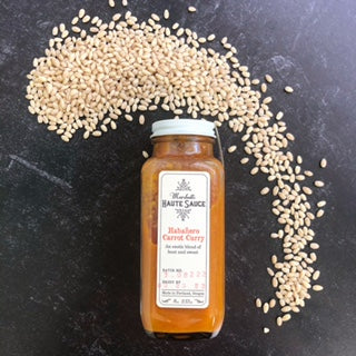 Bottle of Habanero Carrot Curry sauce with pearl barley grains